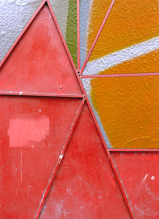 Irregular triangles of red metal door open to reveal graffiti of radiating lines, geometric composition