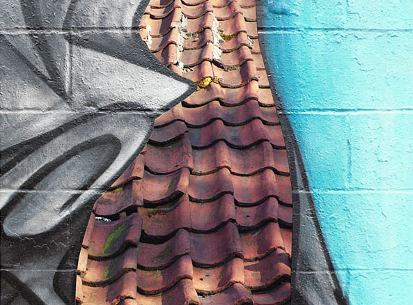 Brooklyn graffiti overlaps terra cotta tiles on the roof of an old farmhouse in Belgium